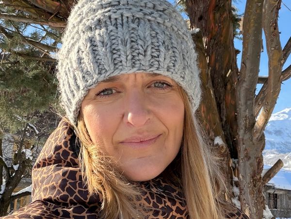 Woman in a gray knit hat and patterned winter jacket outdoors in snowy weather.
