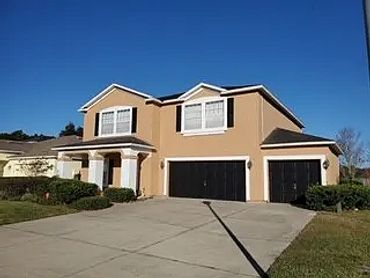 2-story house with beige walls, black doors with white accent trim around the windows, bright blue s