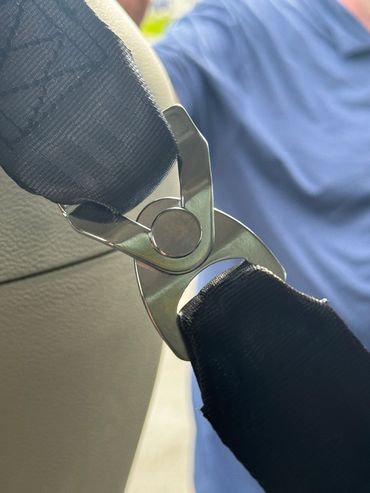 Close-up of a seatbelt latch securing black straps in a car.