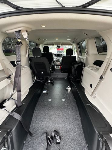 Empty wheelchair-accessible van interior with secured seatbelts and open floor space.