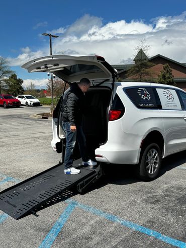 Man stepping into a white accessible van with a ramp.