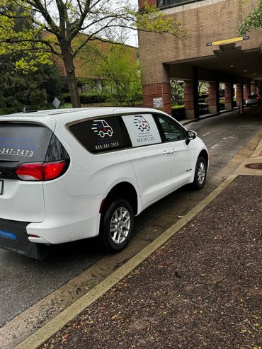 White van for Ohana Care & Transportation parked near a building entrance.