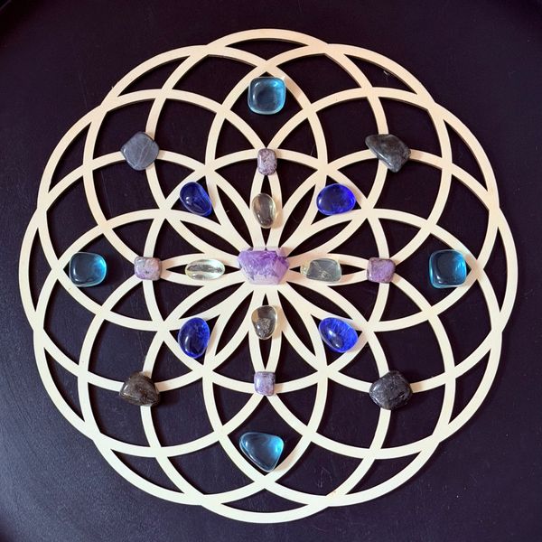 A crystal grid with various stones arranged on a wooden pattern.