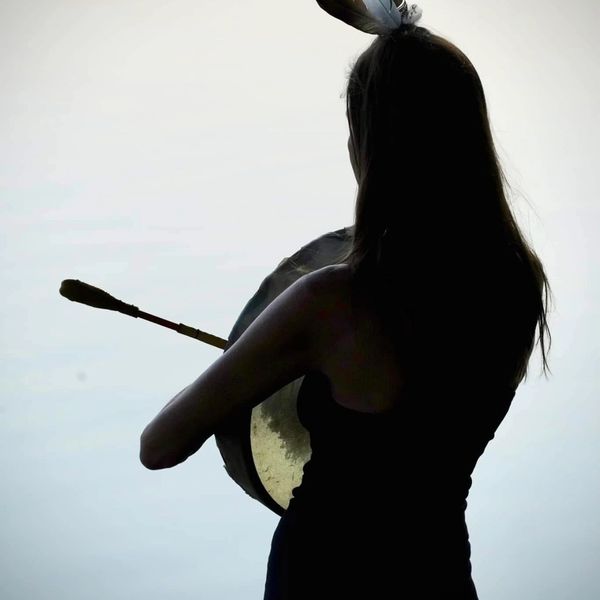 Silhouette of a woman playing a drum.