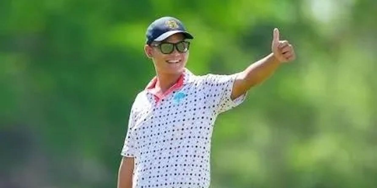 Man smiling and giving thumbs up outdoors.