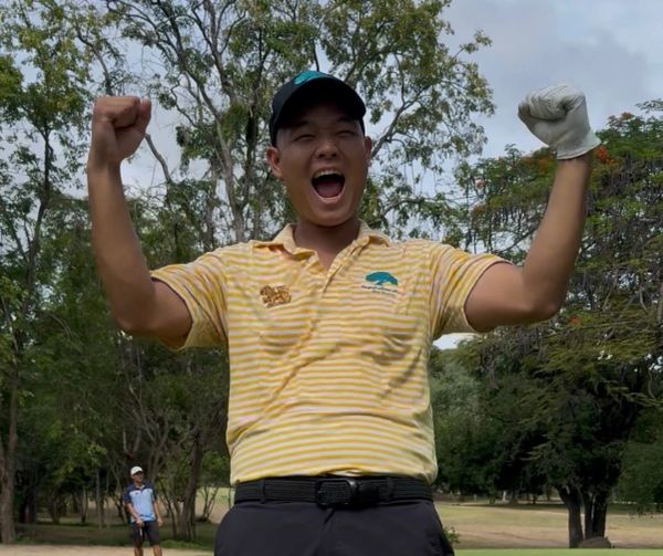 Happy golfer celebrating with arms raised on golf course.