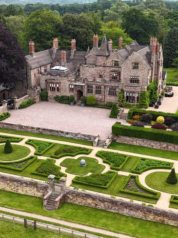 A historic mansion with manicured gardens and lush greenery.