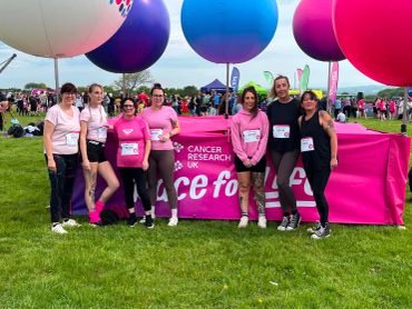 Group of women in front of Cancer Research UK banner at outdoor event.
