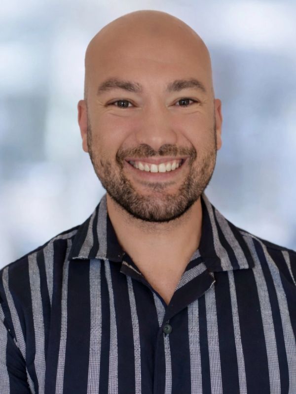 Smiling bald man with a beard wearing a striped shirt.
