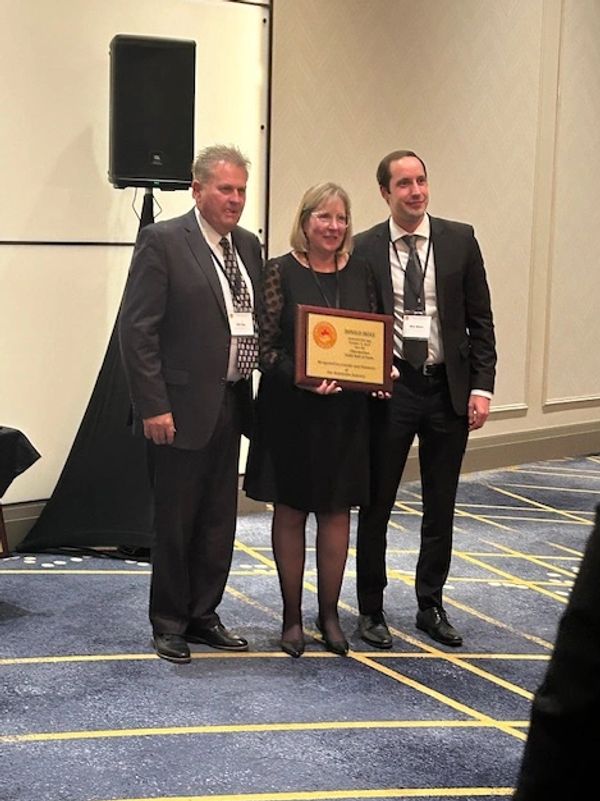 Three people posing with an award plaque.
