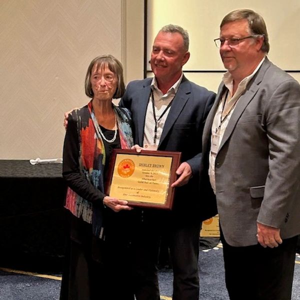 Three people holding an award plaque at an event.