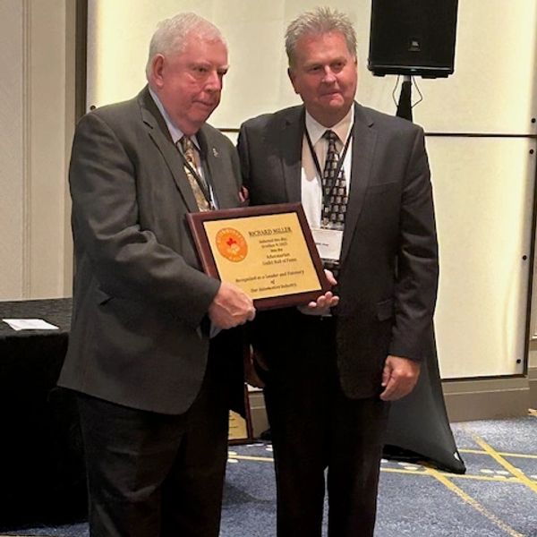 Two men in suits holding an award plaque.