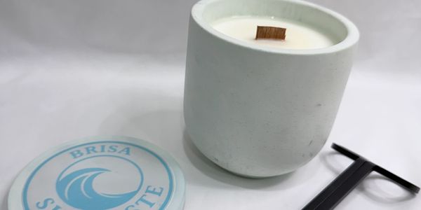 White scented candle in a concrete holder with lid and lighter.