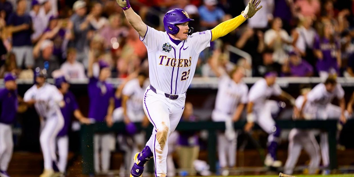 Baseball player in white Tigers uniform celebrates with arms raised on field.
