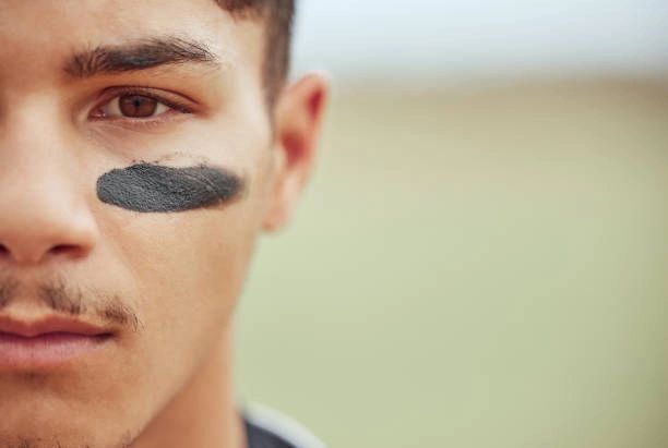 Close-up of a young man with black face paint under his eye.