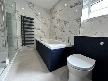 white marbled wall tiles, large walk-in white shower, bath & toilet, chrome fittings, black radiator