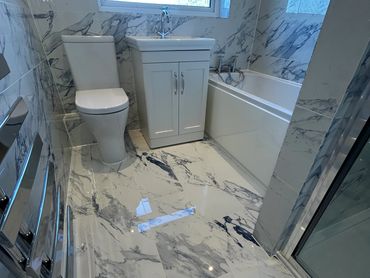 white & grey marble effect wall & floor tiles, chrome wall radiator, white toilet, basin & bath