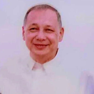 Smiling man in a white shirt against a light background.