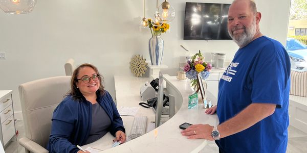 Office manager, Maritza Gomez, is greeting a long time patient and friend at the reception desk.