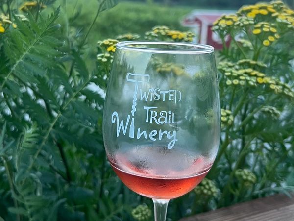 Wine glass with rosé and greenery background.