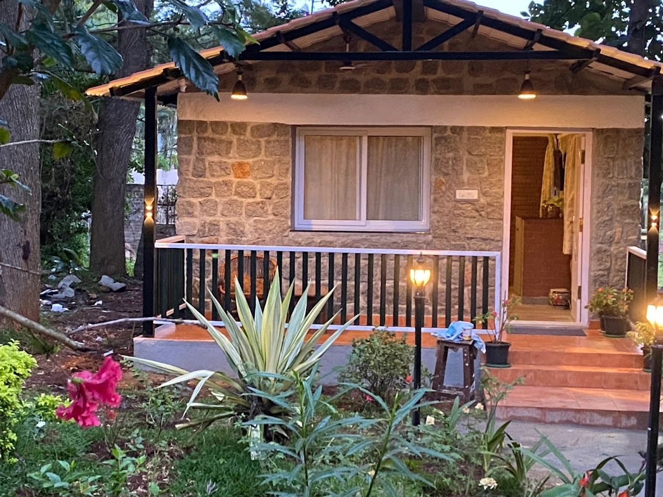 Cozy stone cottage with warm porch lights and lush garden.