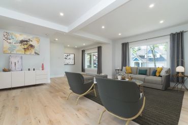 Modern living room with gray chairs, sofa, and large windows.