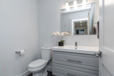Modern bathroom with white fixtures and gray cabinetry.