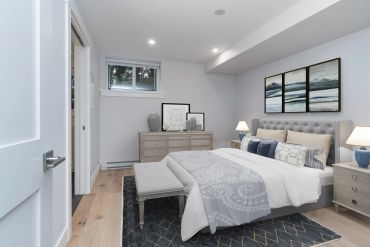 Modern bedroom with neutral tones and blue accents, featuring a tufted bed and abstract wall art.