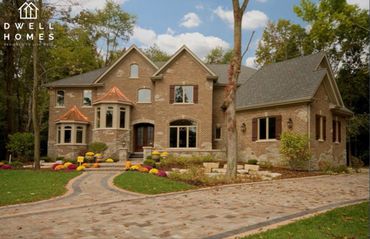 
Grand brick home with arched entrances, gabled roofs, and intricate stone detailing