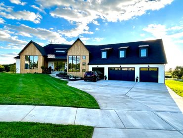 Custom-built home featuring expansive windows, sleek gabled roofs, triple garage