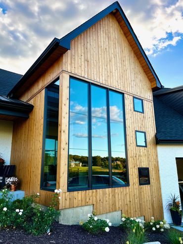 Custom home with towering windows, wood siding, and sharp gable roof design
