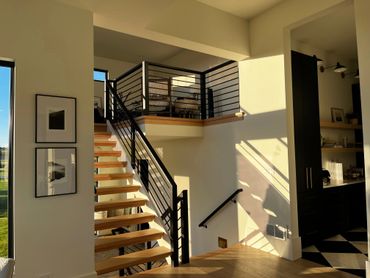 
Modern interior with floating wooden stairs, black railings, and natural light