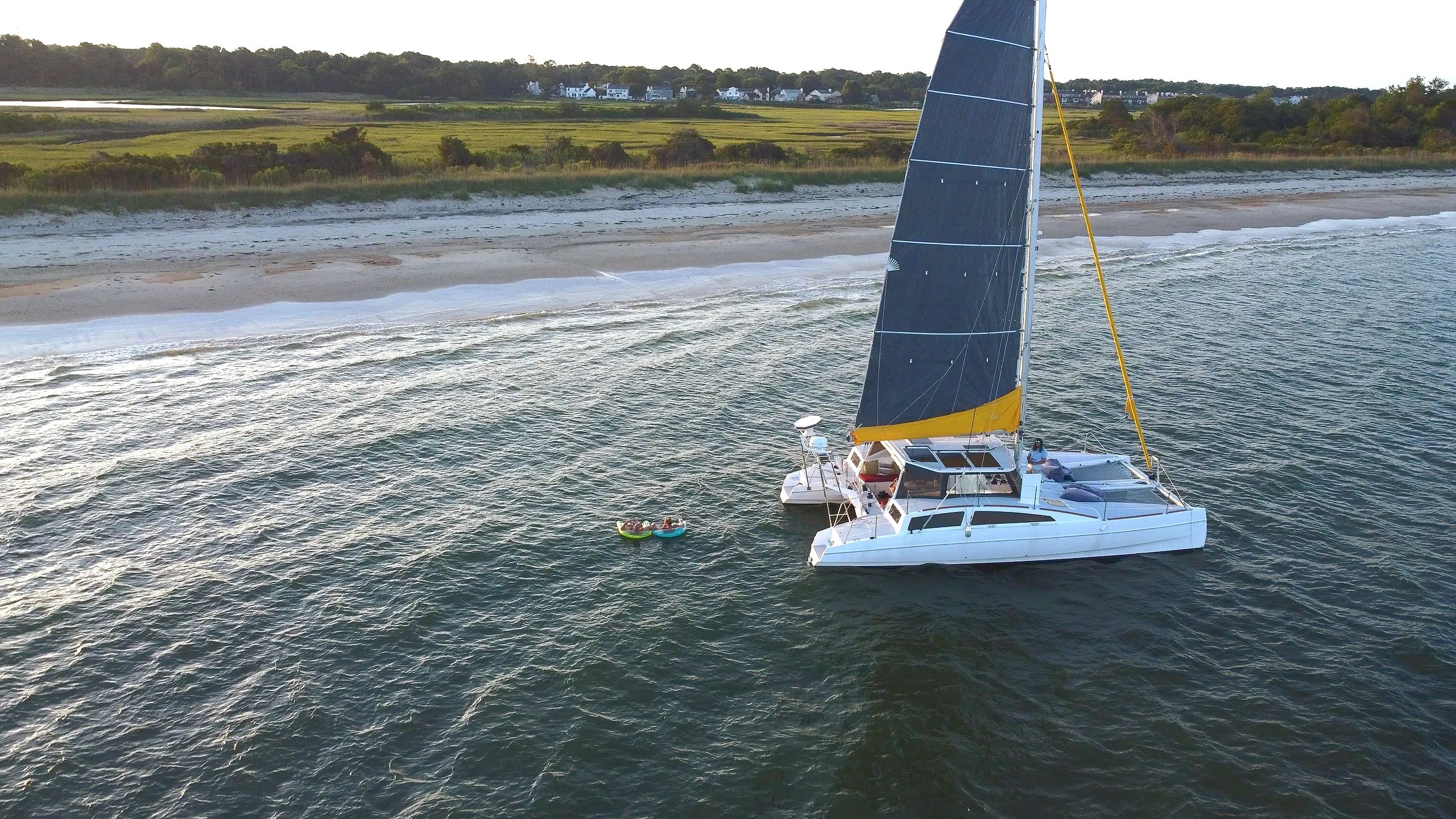Sailing charter with people swimming near the beach on a catamaran boat tour in Hampton Virginia