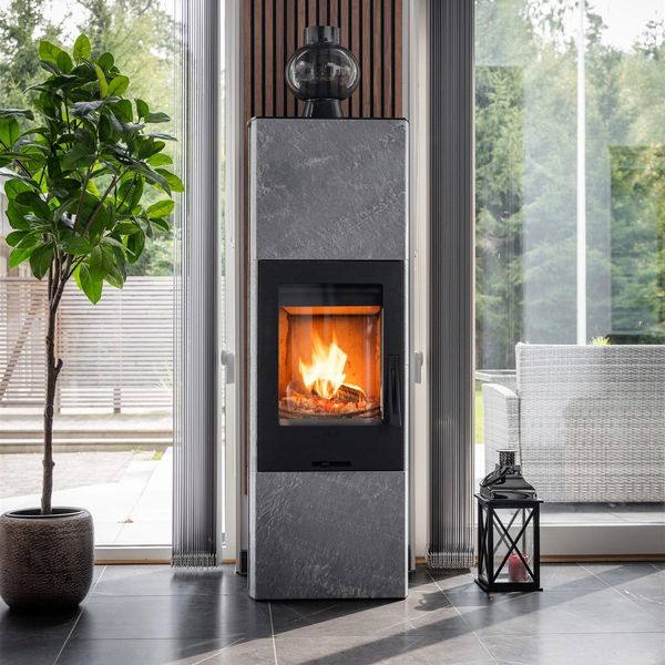 Modern fireplace with fire burning, flanked by a green plant and a lantern indoors.