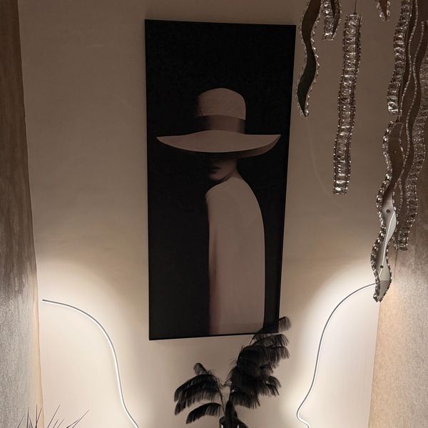 Modern art setup with illuminated face outlines and a stylish portrait of a woman in a hat.