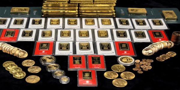 Various gold bars and coins arranged on a black surface.