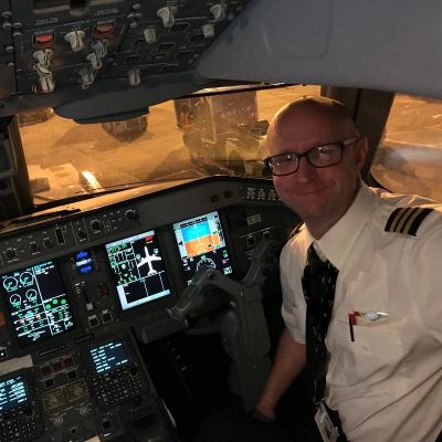 Pilot sitting in an airplane cockpit smiling.