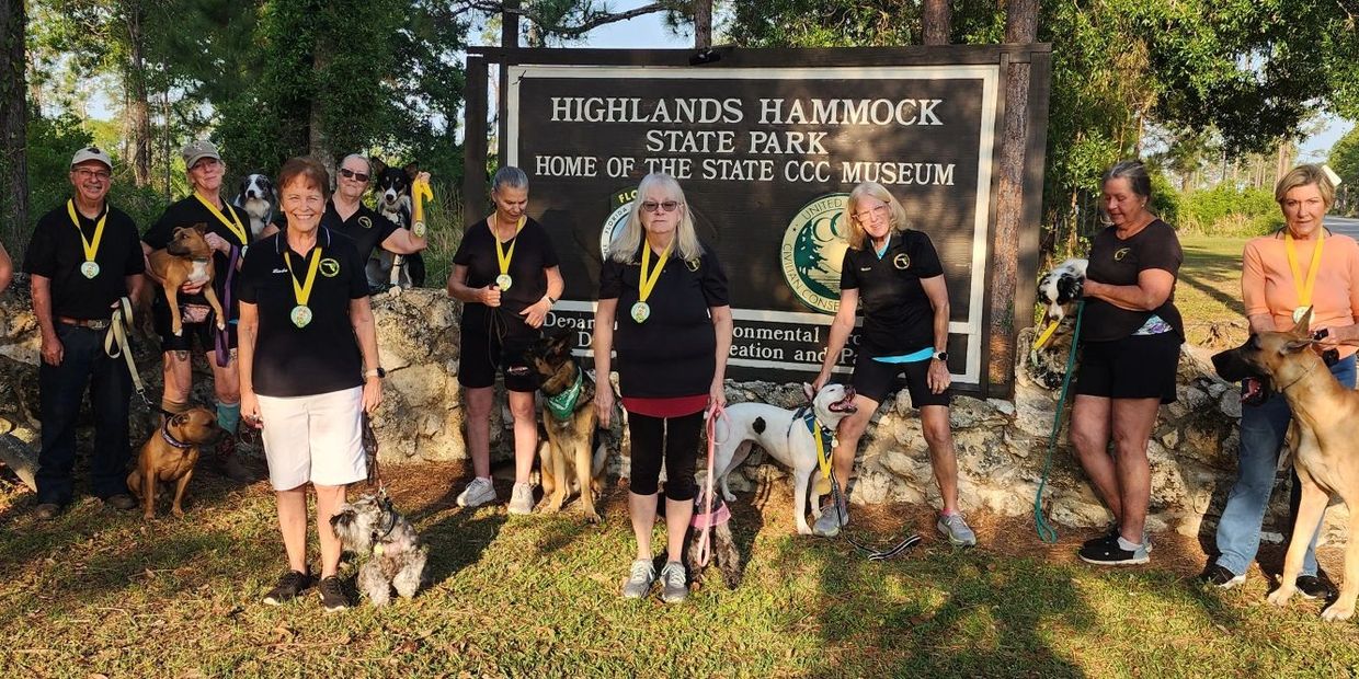 Group of people with dogs wearing medals at Highlands Hammock State Park.