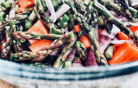Raw asparagus and red pepper salad in rustic bowl