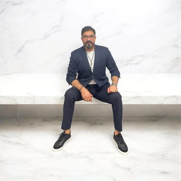 Man in a suit sitting on a white marble bench.