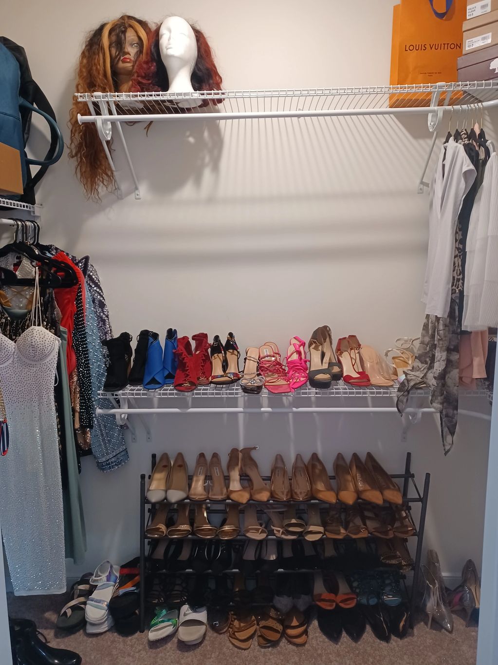 Organized closet with shoes, dresses, and wigs.