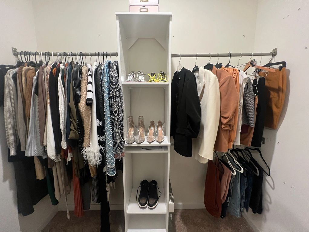 Organized closet with clothes and shoes neatly arranged on racks and shelves.