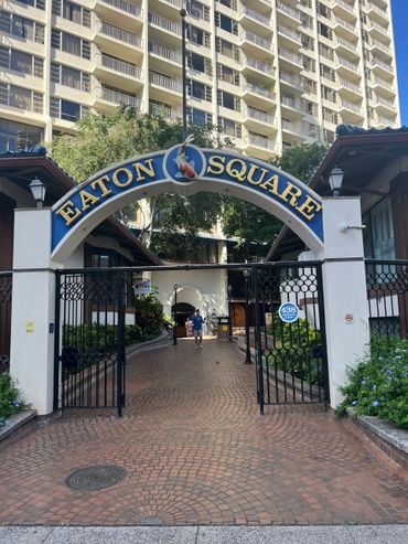 Entrance archway to Eaton Square with a koi fish emblem and gated pathway.