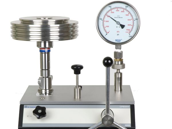 Precision pressure calibration device with dial gauge and control knobs.