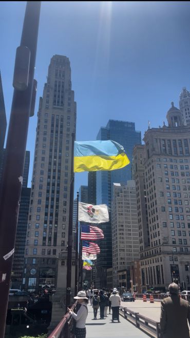 Flags flying in a city on a sunny day.