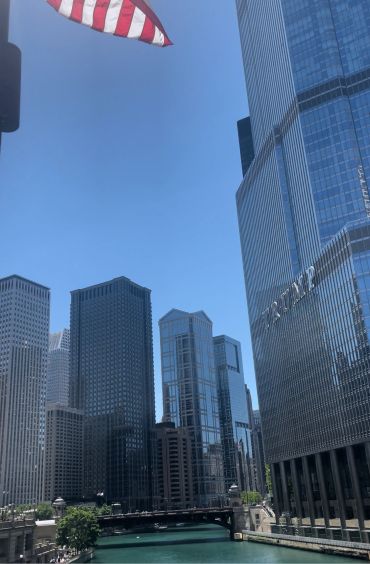 Skyscrapers and river with an American flag overhead.