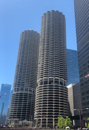 Two cylindrical high-rise buildings under a clear blue sky.