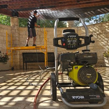 Man pressure washing a covered patio using a Ryobi power washer.