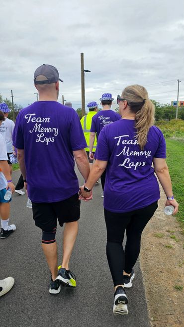 Couple holding hands walking at Alzheimer's charity event.