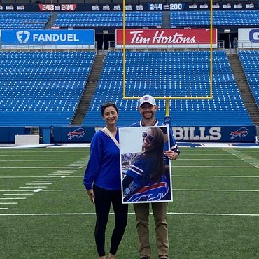 Couple honoring family member who has passed standing on football field.